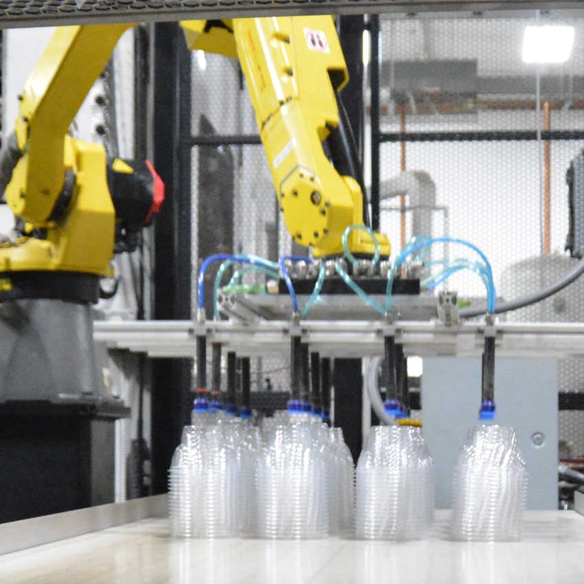 MinnTech Plastics FANUC robotic arm with suction cups picking thermoformed PET containers on production line