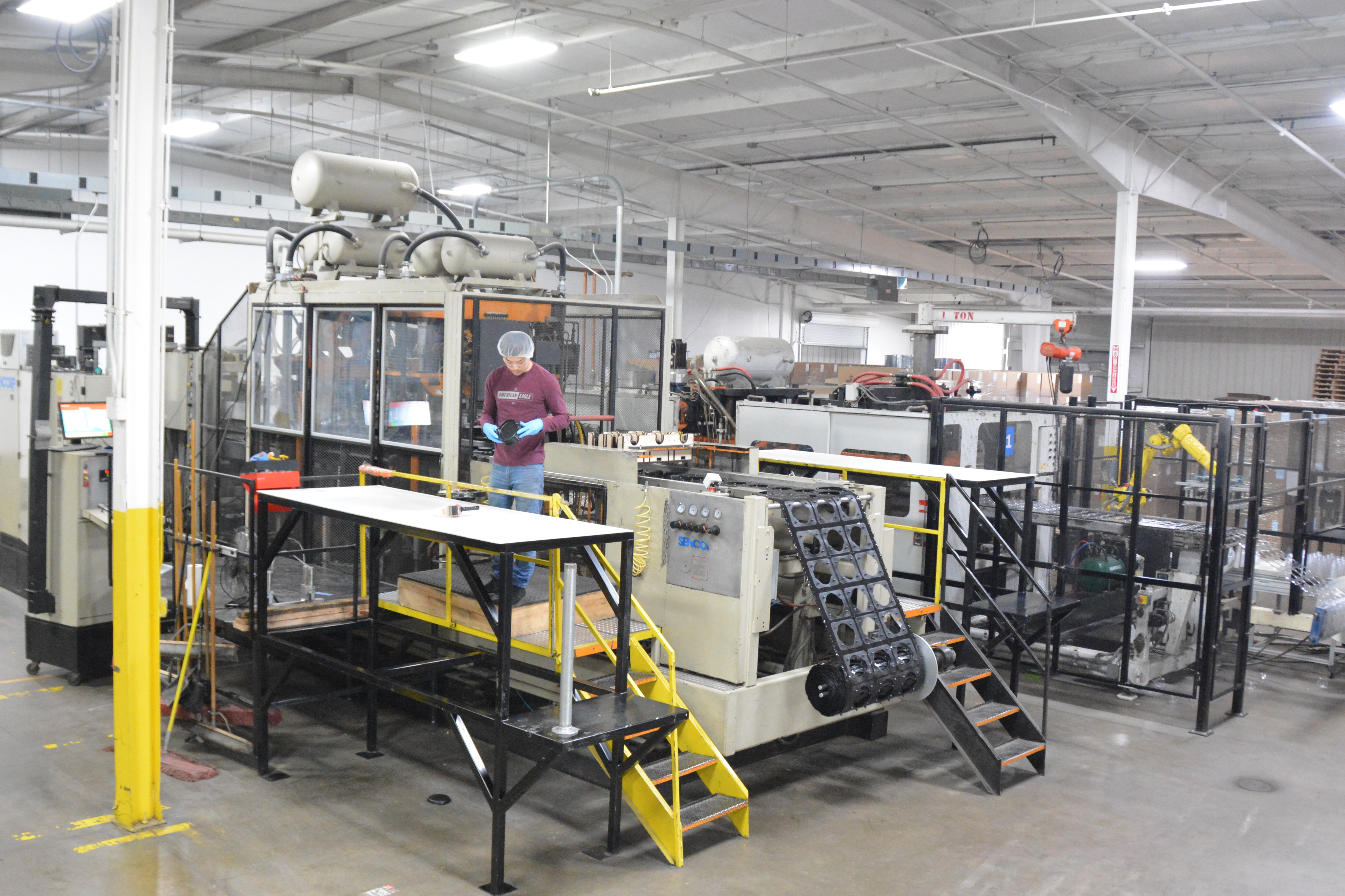 MinnTech Plastics thermoforming production floor with operator managing inline forming equipment